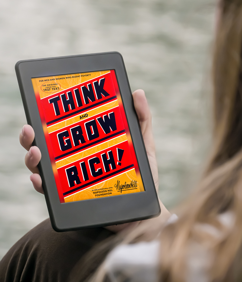 Person holding Kindle with Think and Grow Rich by Napoleon Hill