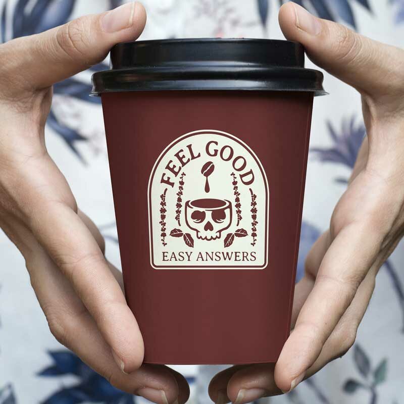 White hands hold coffee cup with skull logo that reads "Feel good, easy answers" referencing Ananad Giridharadas's book "Winners Take All"